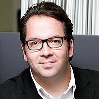 Portrait von männlichem Mitarbeiter mit Brille.