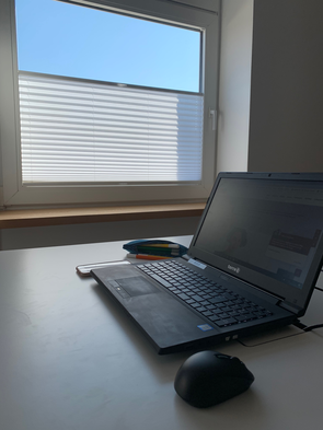 Bild von sporadischem Schreibtisch mit Laptop und sonnengeschütztem Arbeitsplatz.