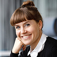 Portrait von lächelnder Frau mit hochgesteckten braunen Haaren.